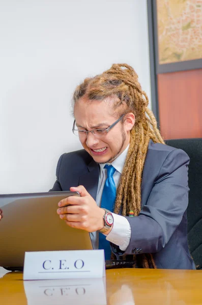 Beau homme avec des craintes et costume d'affaires assis par bureau tenant sur l'écran d'ordinateur portable, expression faciale frustrée, concept de jeune manager — Photo