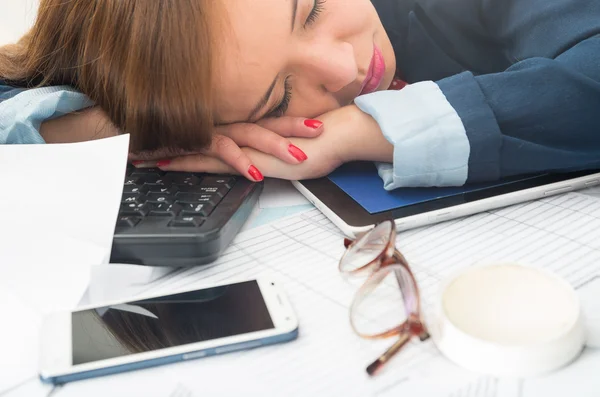 Bürofrau beugt sich über weißen Schreibtisch oder schläft mit Computertastatur, Brille und Handy ausgebreitet — Stockfoto