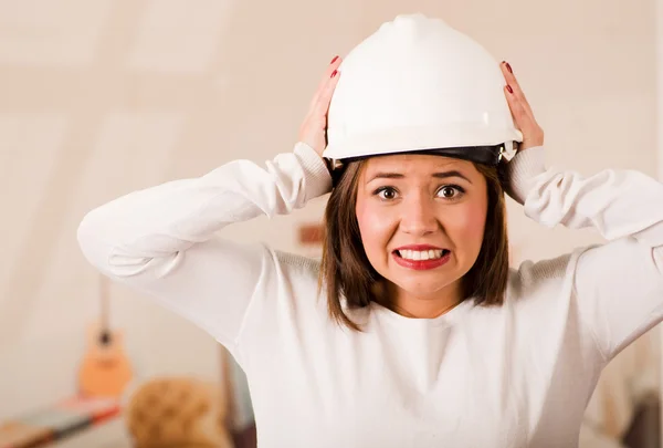 건축용 헬멧을 쓰고 있는 젊은 여자, 좌절하고 화가 난 신체 언어로 보이는 카메라 앞에 서 있다 — 스톡 사진