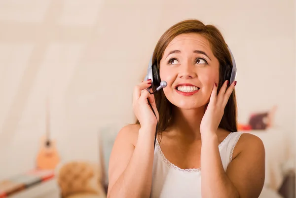 Young woman wearing white top and headset facing camera while interacting smiling, stressed concept — Stock Photo, Image