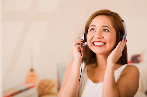 Young woman wearing white top and headset facing camera while interacting smiling, stressed concept — Stock Photo, Image