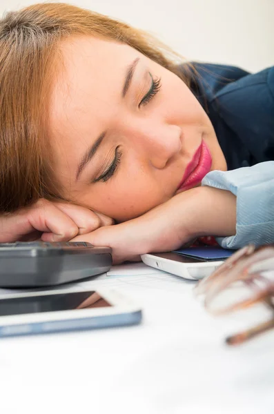 Mujer de oficina doblada sobre escritorio blanco descansando o durmiendo con el teclado de la computadora, gafas y móvil extendido —  Fotos de Stock