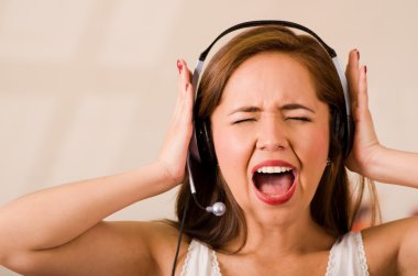 Beyaz bluz ve kulaklık takan genç bir kadın kameraya bakarken hayal kırıklığına uğramış yüz ifadesi, stresli konsept