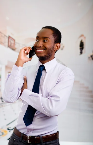 Knappe man met overhemd en stropdas permanent in ontvangsthal praten op mobiele telefoon, bedrijfsconcept — Stockfoto
