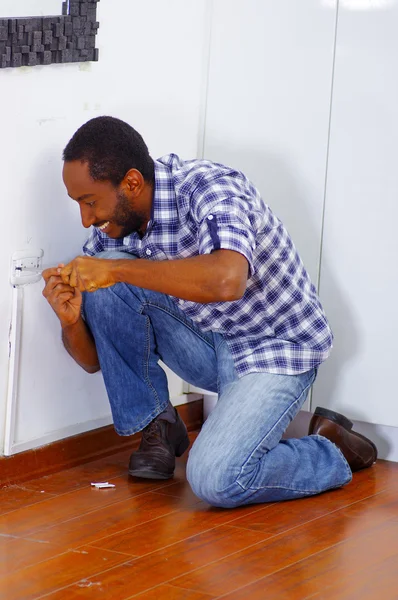 Homme portant chemise blanche et bleue travaillant sur prise murale électrique à l'aide de tournevis, concept électricien — Photo