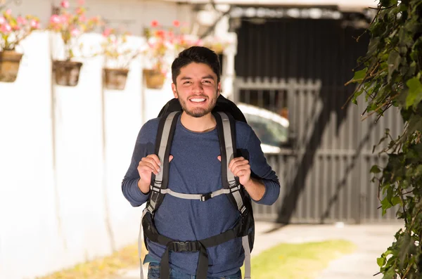 Young happy man wearing casual clothes and backpack posing for camera, smiling, garden environment, backpacker concept — Stock Photo, Image