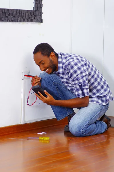 Homme portant chemise blanche et bleue travaillant sur des fils de prise murale électrique à l'aide de multimètre, concept électricien — Photo