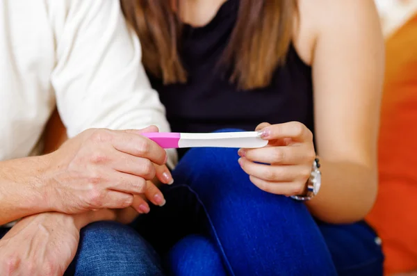 Paar setzt sich hin, hält Schwangerschaftstest zwischen sich, schwangeres Konzept — Stockfoto