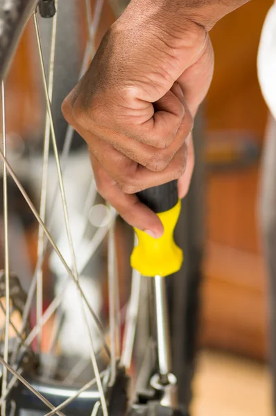Fechar a mão segurando multi chave de fenda trabalhando em peças mecânicas ao lado de raios de roda — Fotografia de Stock