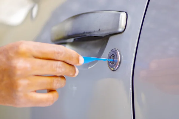 Primeros planos manos de cerrajero utilizando herramientas de selección para abrir la puerta del coche con llave — Foto de Stock