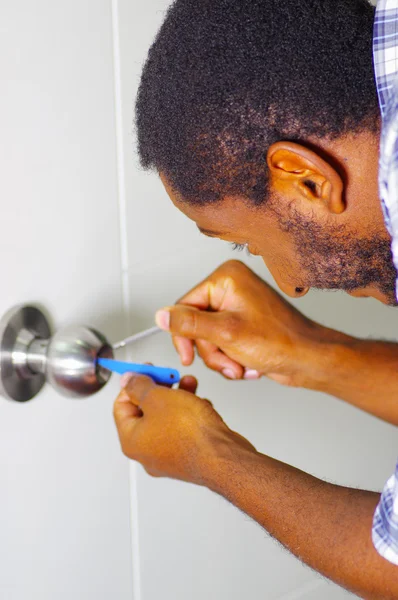 Closeup head and hands of locksmith using pick tools to open locked door — Stock Photo, Image