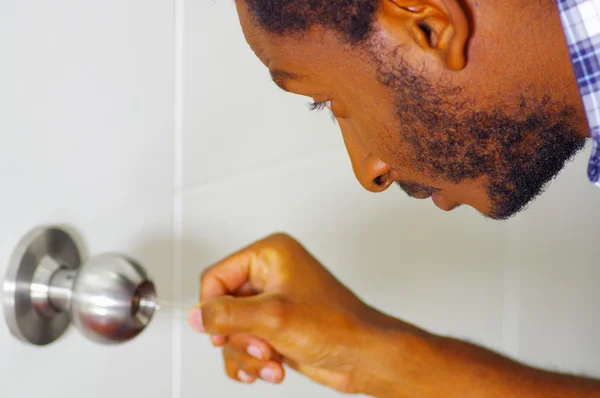 Closeup head and hands of locksmith using pick tools to open locked door — Stock Photo, Image