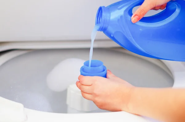 Крупным планом женские руки наливая моющее средство в для измерения чашки для стиральной машины, концепции стирки по дому — стоковое фото