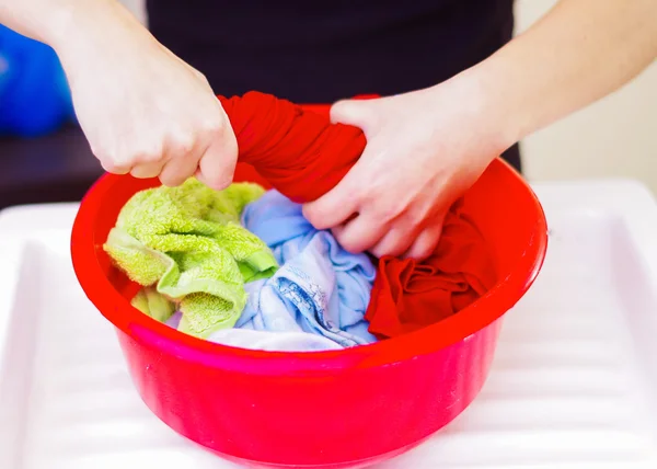 特写镜头女性手洗手衣服在红色塑料洗脸桶, 擦洗和挤压织物, 洗衣家务的概念 — 图库照片
