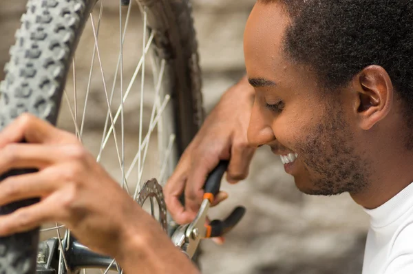 Man wearing white shirt happy working on repairing bicycle mechanics using screwdriver tool