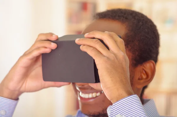 Człowiek na sobie niebieską koszulę wirtualnym rzeczywistość mobilne urządzenie do badania, trzymając okulary przed oczy i uśmiechając się — Zdjęcie stockowe