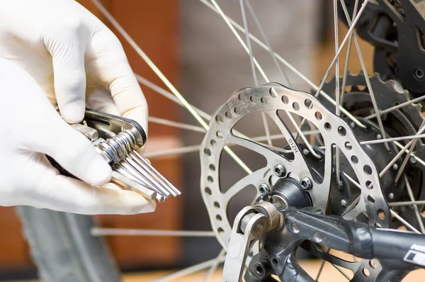 紧身衣手戴白色手套持有多 unbrako 关键工具旁边的自行车车轮的部分, 机械维修的概念 — 图库照片