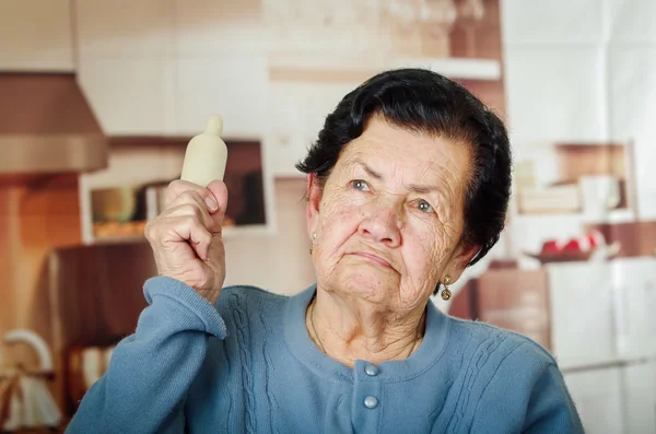 Older cute hispanic woman in blue sweater holding up a rolling pin