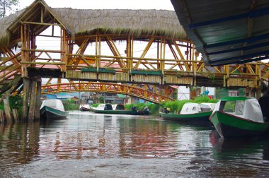 Pasto, Kolombiya - 3 Temmuz 2016: la cocha göl kenarında küçük bir ahşap köprü altında Nehri üzerinde park edilmiş bazı küçük tekneler