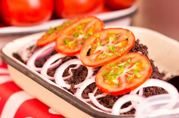 White tray on a table with dry and fried lamb blood, tomatoes and onions decorating this — Stock Photo, Image