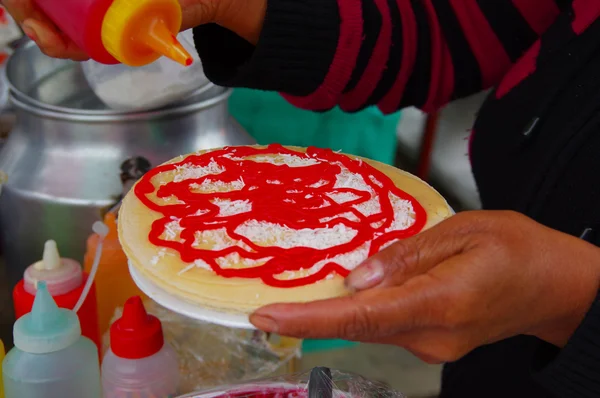 PASTO, COLOMBIE - 3 JUILLET 2016 : femme préparant un dessert avec des gaufrettes, du sirop de fraise et de la noix de coco — Photo