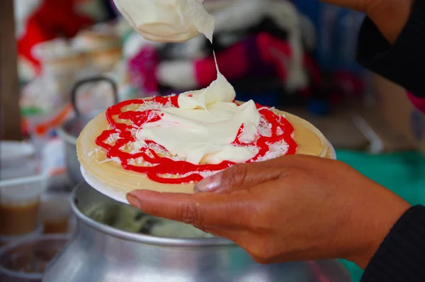 PASTO, COLOMBIA - 3 DE JULIO DE 2016: mujer agregando un poco de crema a una oblea con jarabe de fresa y coco — Foto de Stock