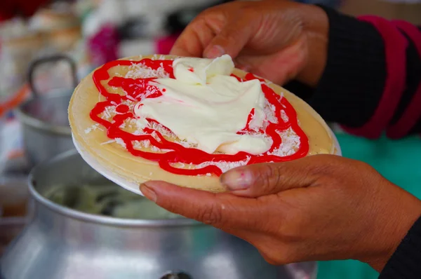 Pasto, Colombia - 3 juli 2016: kvinna förbereder en dessert gjord med en wafer, strawberry sirap, kokos och grädde — Stockfoto