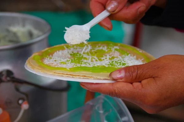 PASTO, COLOMBIE - 3 JUILLET 2016 : Une femme ajoute de la noix de coco à une galette avec du sirop de kiwi — Photo