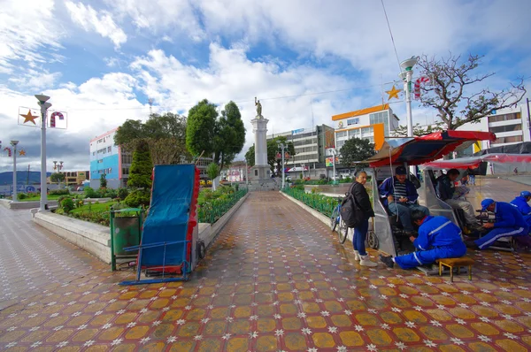 TULCAN, ECUADOR - 3 de julio de 2016: hombres limpiando los zapatos de algunas personas no identificadas en el parque central de la ciudad —  Fotos de Stock