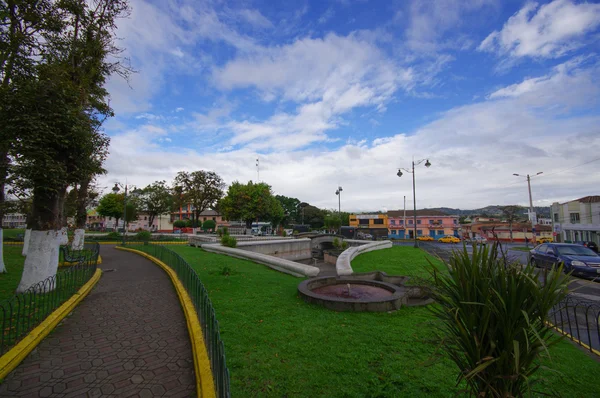 TULCAN, ECUADOR - 3 DE JULIO DE 2016: algunos automóviles que conducen por la calle junto a un parque vacío en un día nublado —  Fotos de Stock