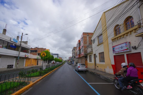 TULCAN, ECUADOR - 3 DE JULIO DE 2016: hombre conduciendo una motocicleta con un pasajero en una pequeña calle de la ciudad — Foto de Stock