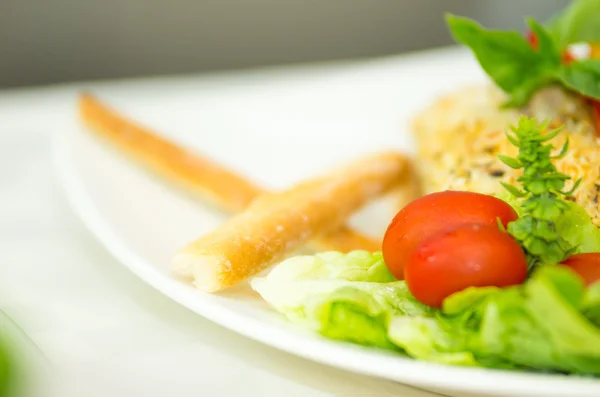 Closeup fresh colourful salad with cherry tomatoes, green veggies and some crackers mixed together on white plate — Stock Photo, Image