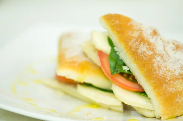 Delicious cheese, albahaca basil and tomato ciabatta sandwich on white plate — Stock Photo, Image