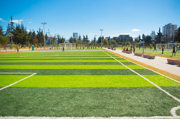 Quito, Ecuador - 8 augusti 2016: fotbollsplaner ligger i innerstaden park La Carolina, grönt konstgräs yta, byggnader synlig bakgrund, vacker solig dag — Stockfoto