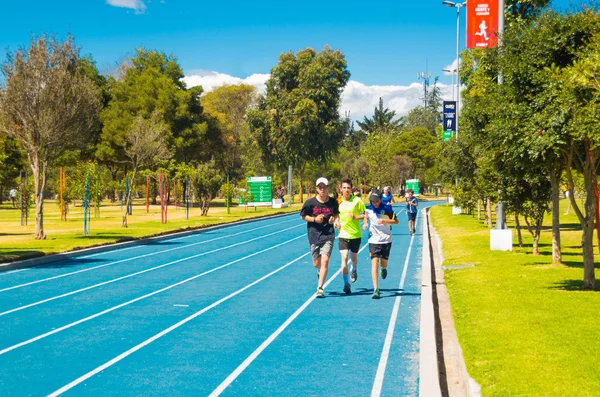 QUITO, ECUADOR - 8 AGOSTO, 2016: Pista atlética de color azul ubicada en el parque interior de la ciudad La Carolina, corredores acercándose a la cámara, hermoso día soleado — Foto de Stock