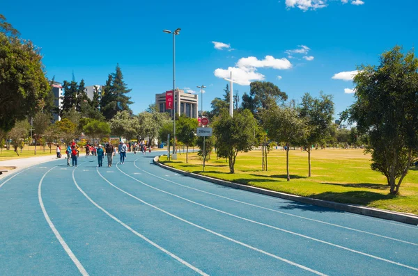 QUITO, ECUADOR - 8 AGOSTO, 2016: Pista atlética de color azul ubicada en el parque interior de la ciudad La Carolina, personas caminando acercándose a la cámara, hermoso día soleado — Foto de Stock