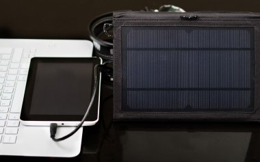 Nice siyah taşınabilir güneş şarj masasının üstünde oturan, tablet bağlı, beyaz dizüstü bilgisayar, modern iş teknolojisi kavramı, stüdyo arka plan