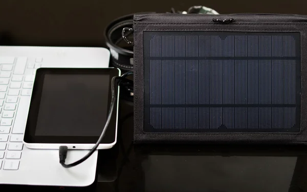 Nice carregador solar portátil preto sentado em cima da mesa, tablet conected, laptop branco, conceito de tecnologia de negócios moderna, fundo do estúdio — Fotografia de Stock