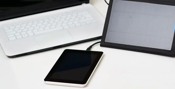 Nice black portable solar charger and a small tablet sitting next to exclusive white laptop, modern business technology concept, studio background — Stock Photo, Image