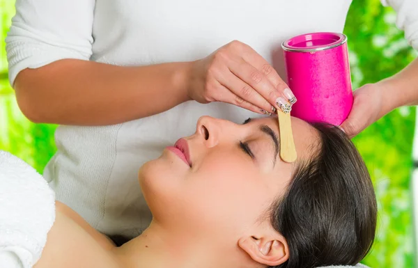 Closeup womans face receiving facial hair waxing treatment, hand using wooden stick to apply wax, beauty and fashion concept — Stock Photo, Image