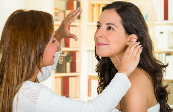 Cosmetoloog het uitvoeren van gezichts ontharing met behulp van threading techniek op brunette patiënt glimlachend — Stockfoto