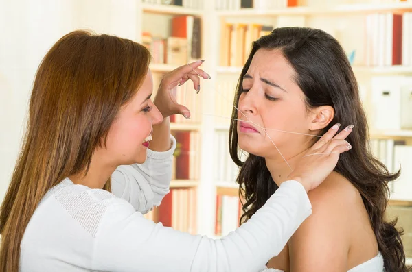 Cosmetoloog het uitvoeren van gezichts ontharing met behulp van threading techniek op brunette patiënt met pijnlijke gezichtsuitdrukkingen — Stockfoto