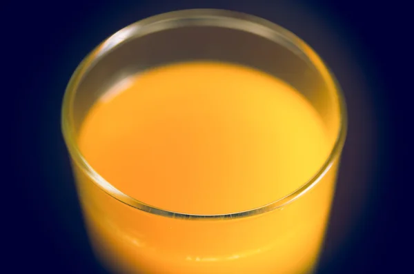 Primer plano del zumo de naranja bellamente coloreado en un vaso transparente disparado desde el ángulo lateral superior — Foto de Stock