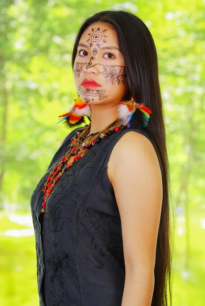 Portret Amazone exotische vrouw met Facial Paint en zwarte jurk, trots poseren voor camera, forest achtergrond. — Stockfoto