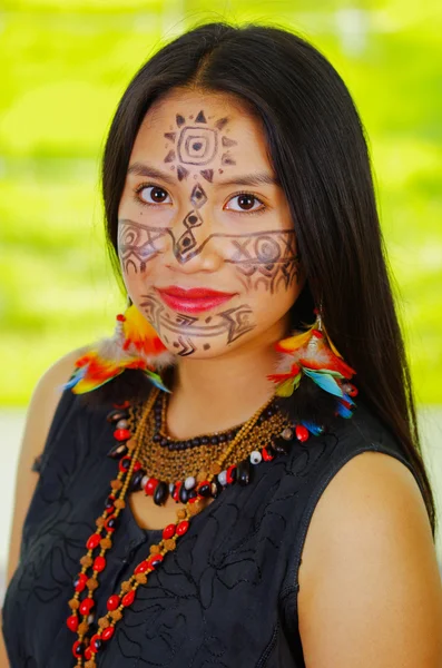 Porträt amazonische exotische Frau mit Gesichtsbemalung und schwarzem Kleid, posiert stolz für die Kamera, Waldhintergrund. — Stockfoto