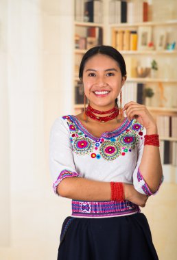 Siyah etek giyen genç ve güzel bir avukat. Kolyeli geleneksel bir Andy bluzu. Kameraya poz veriyor, mutlu bir şekilde gülümsüyor.