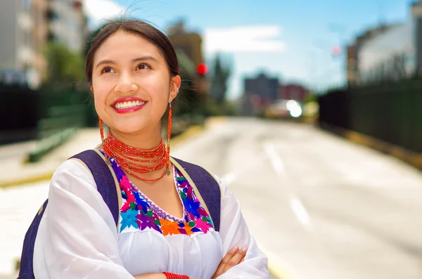 Mujer joven y bonita con blusa andina tradicional y mochila azul, esperando el autobús en la plataforma de la estación al aire libre, sonriendo felizmente —  Fotos de Stock