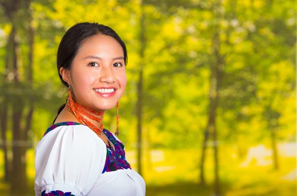 Красивая молодая женщина, одетая в традиционную андскую блузку с ожерельем, стоящая перед камерой, счастливо улыбающаяся, зеленый лес — стоковое фото