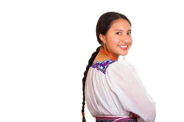 Красивая молодая женщина стоит в традиционной андской блузке и красном ожерелье, поворачивая голову, глядя в камеру, улыбаясь счастливо, белый студийный фон — стоковое фото