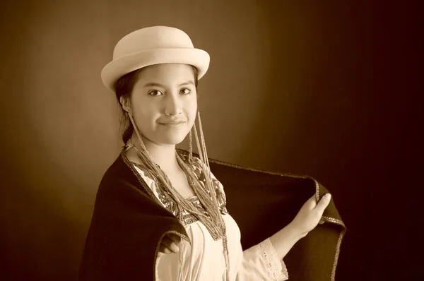Prachtige Spaanse model dragen van Andes traditionele kleding, vasthouden aan donkere poncho bovenop met bijpassende hoed, glimlachend poseren voor camera, studio achtergrond, zwart-wit editie — Stockfoto